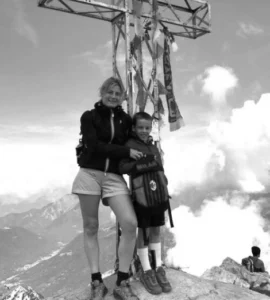 Chiara Marelli e il Figlio Giacomo appoggiata a una croce di ferro in montagna