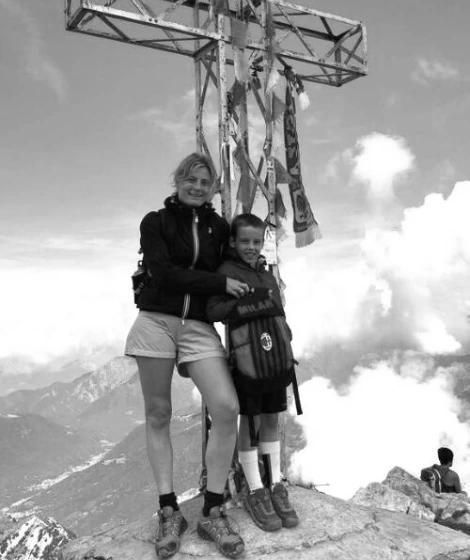 Chiara Marelli e il Figlio Giacomo appoggiata a una croce di ferro in montagna